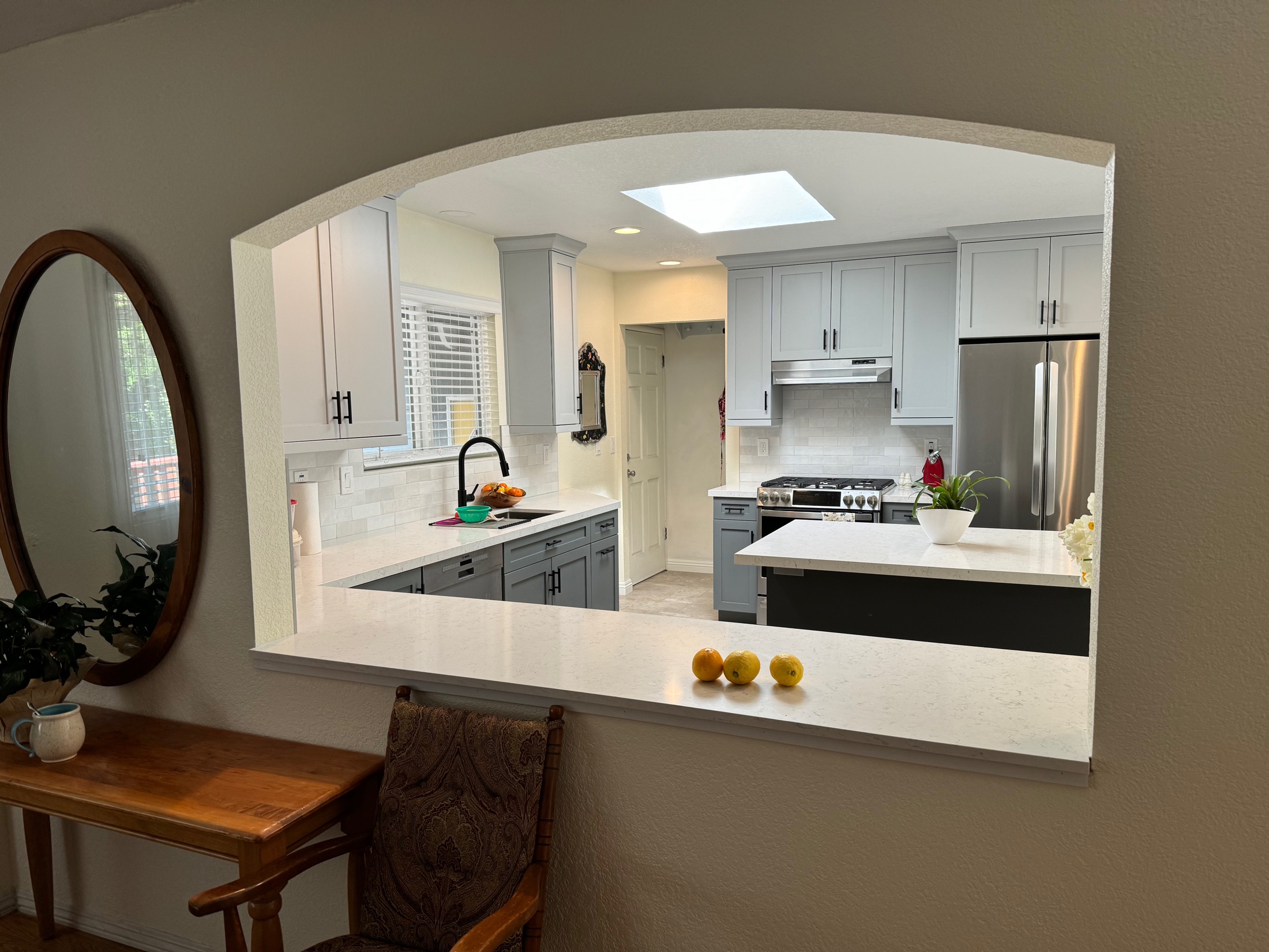 Aromas kitchen viewed through arched pass-through with gray cabinetry