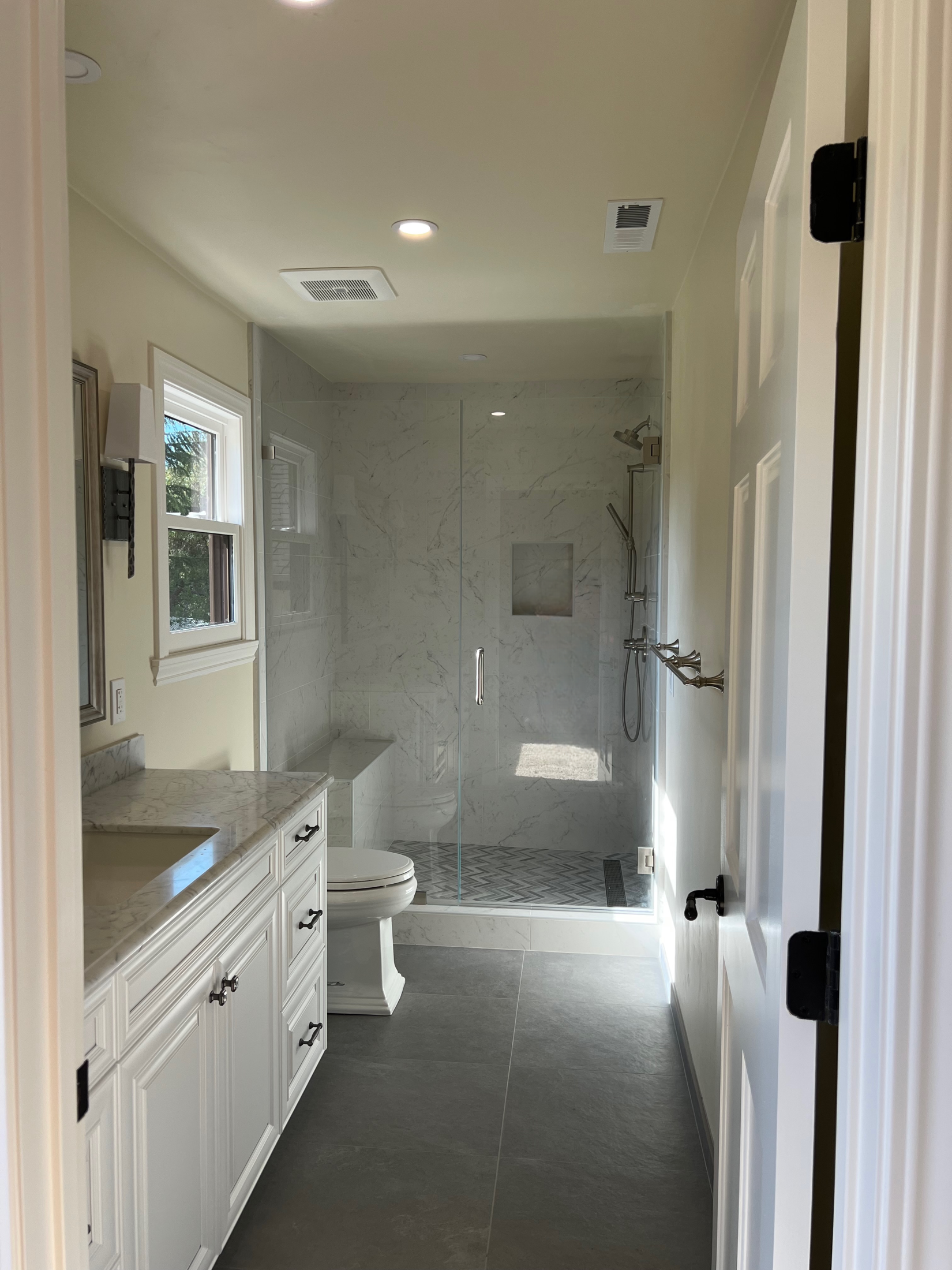 Carmel Valley master bathroom with Carrara marble walls and herringbone marble floor