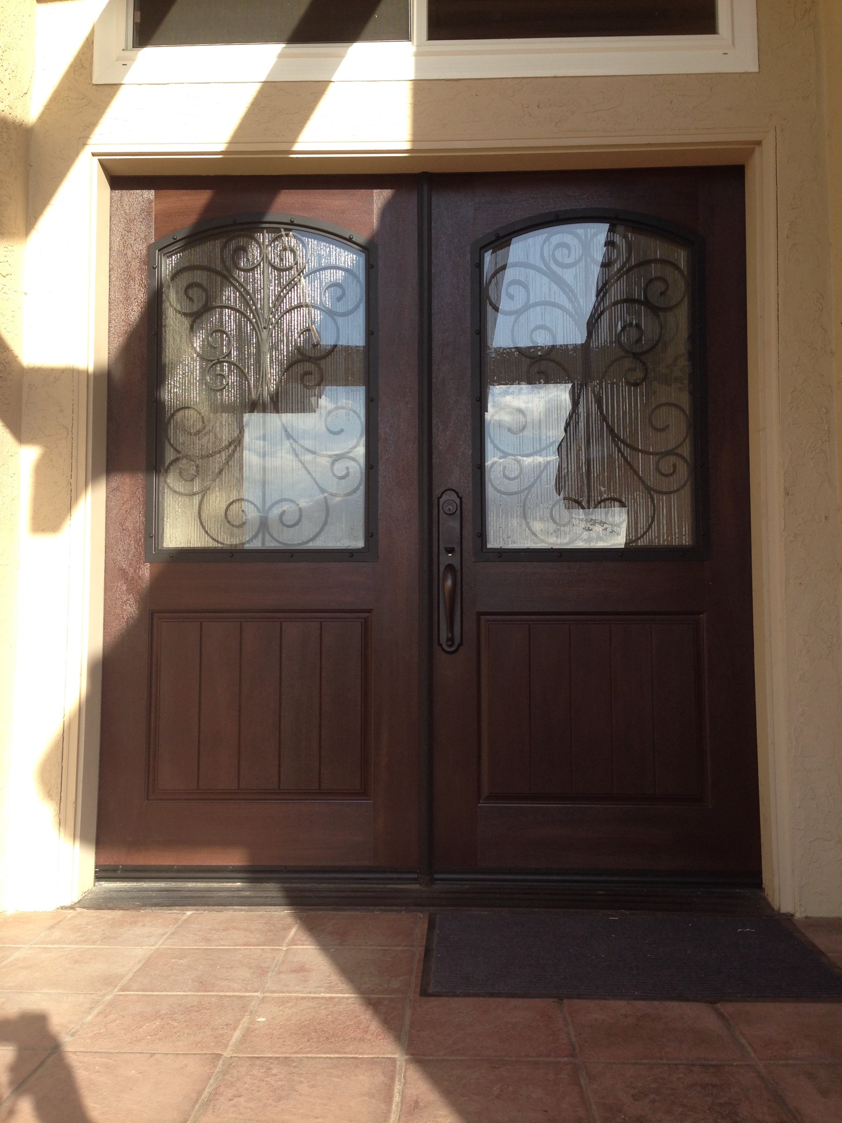 Custom dark-stained entry doors with wrought-iron grilles in Discovery Bay home