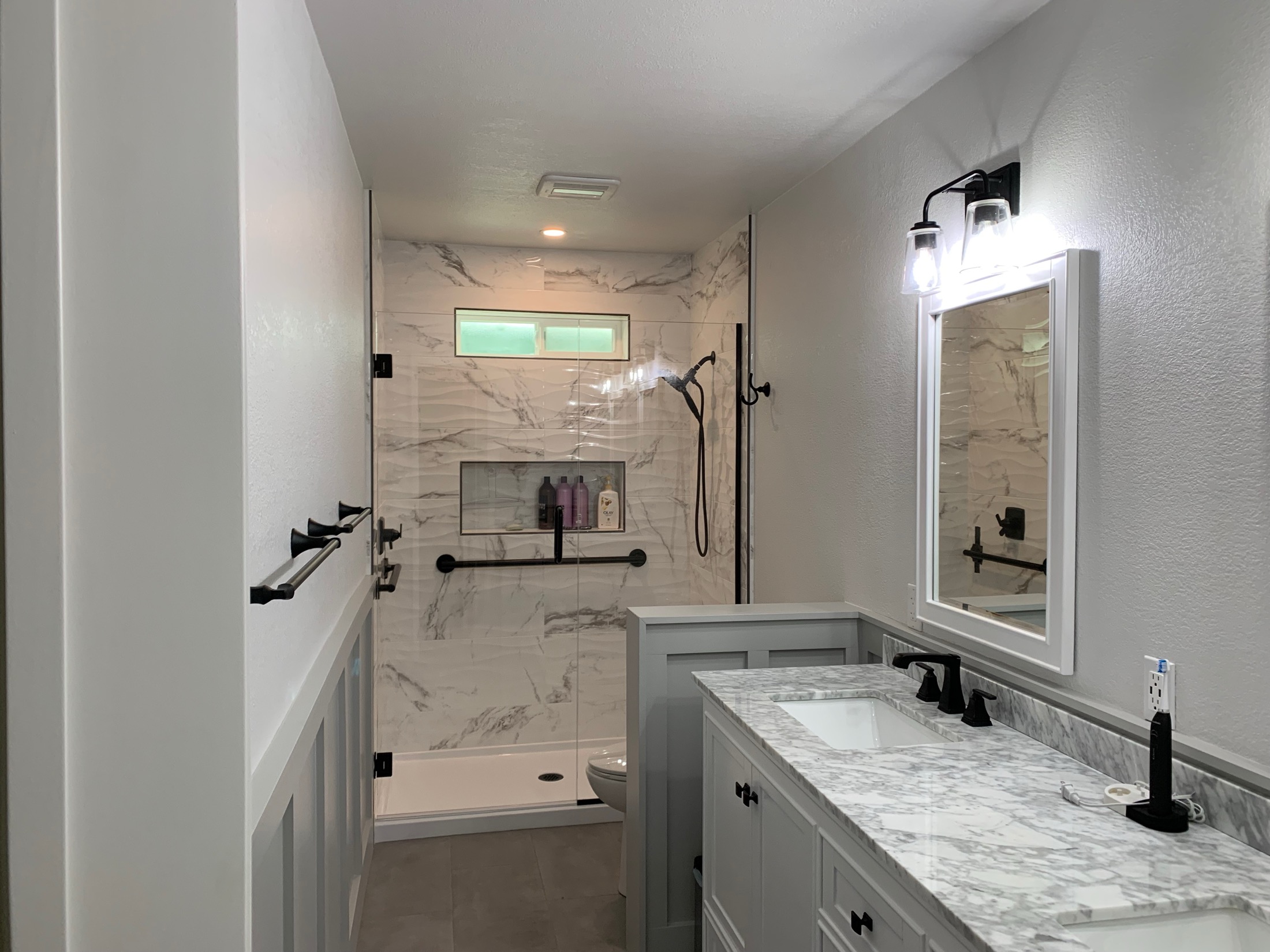 Hollister bathroom remodel with marble-look walk-in shower and wainscoting