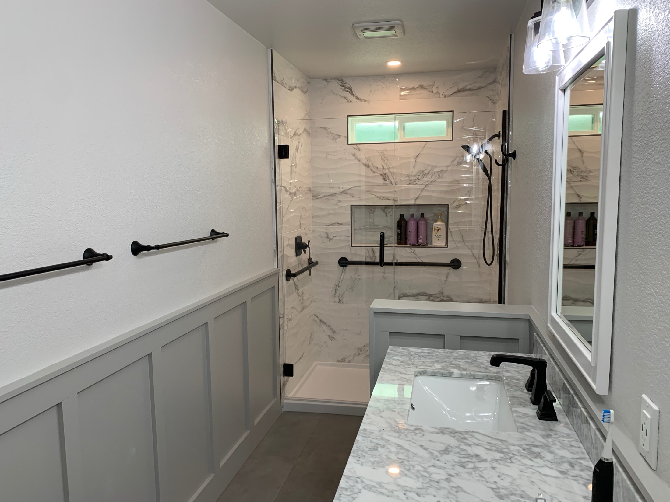Hollister bathroom featuring wavy-textured marble accent wall in shower