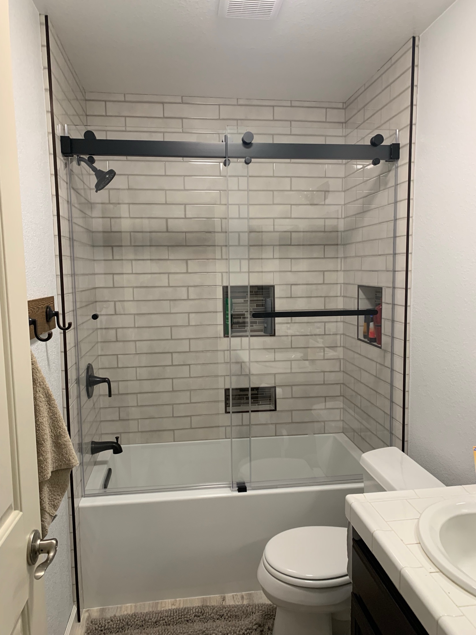 Hollister bathroom with white subway tile tub-shower combo and matte black hardware