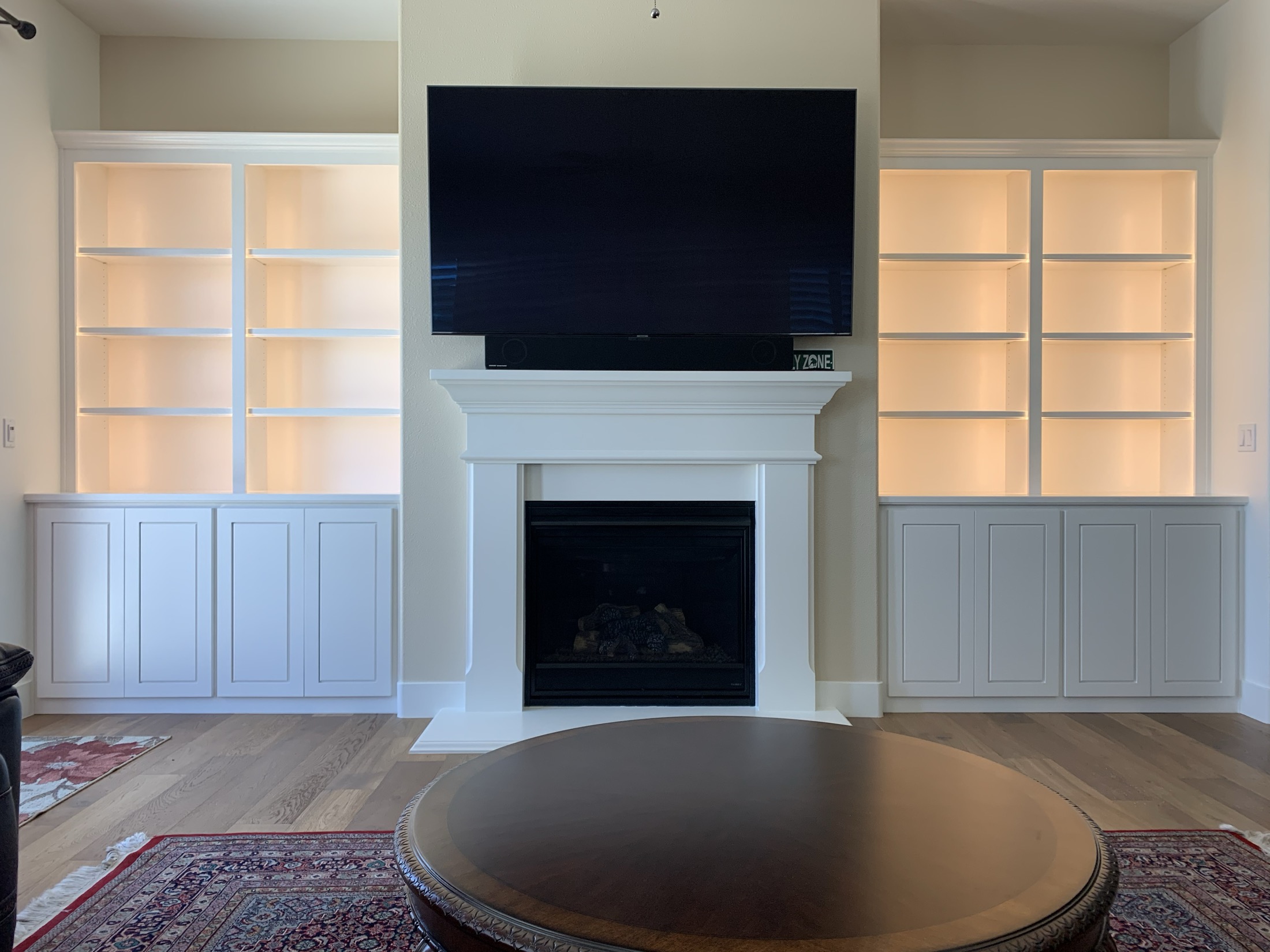 Custom white backlit built-in cabinetry flanking gas fireplace in Hollister home