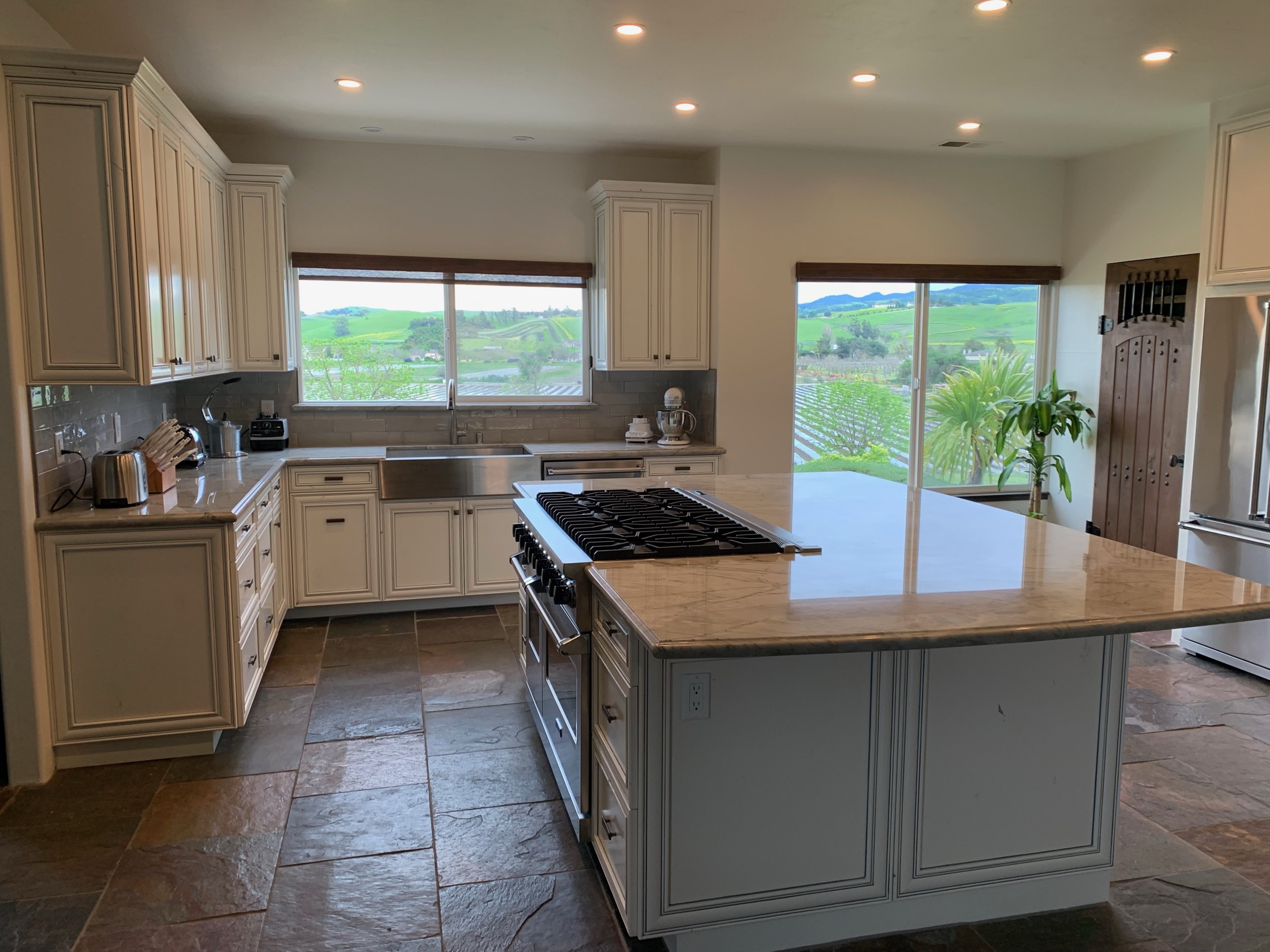 Hollister kitchen with antique white cabinetry, marble island, slate tile floor