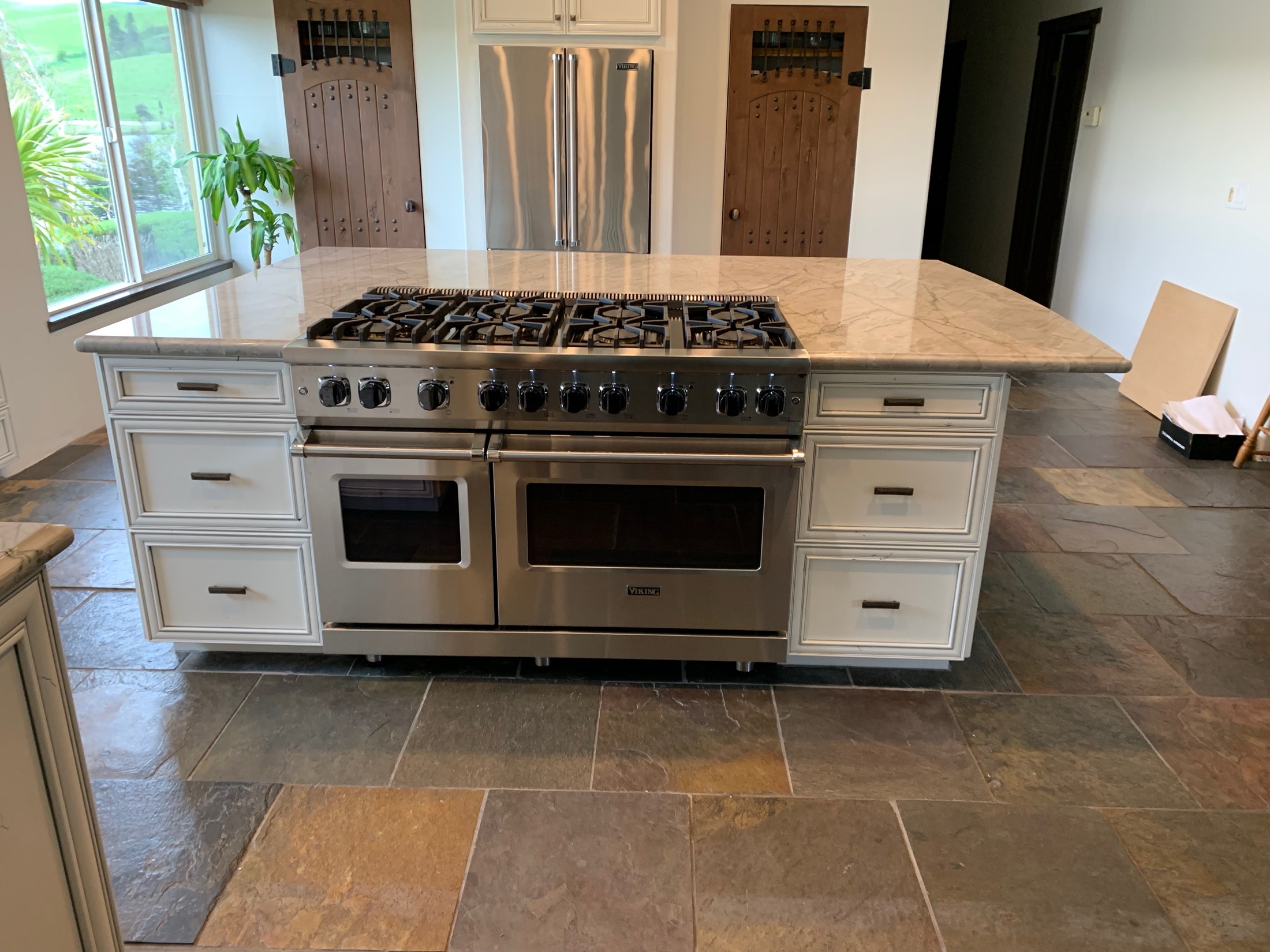 Viking range and double oven on marble island in Hollister kitchen